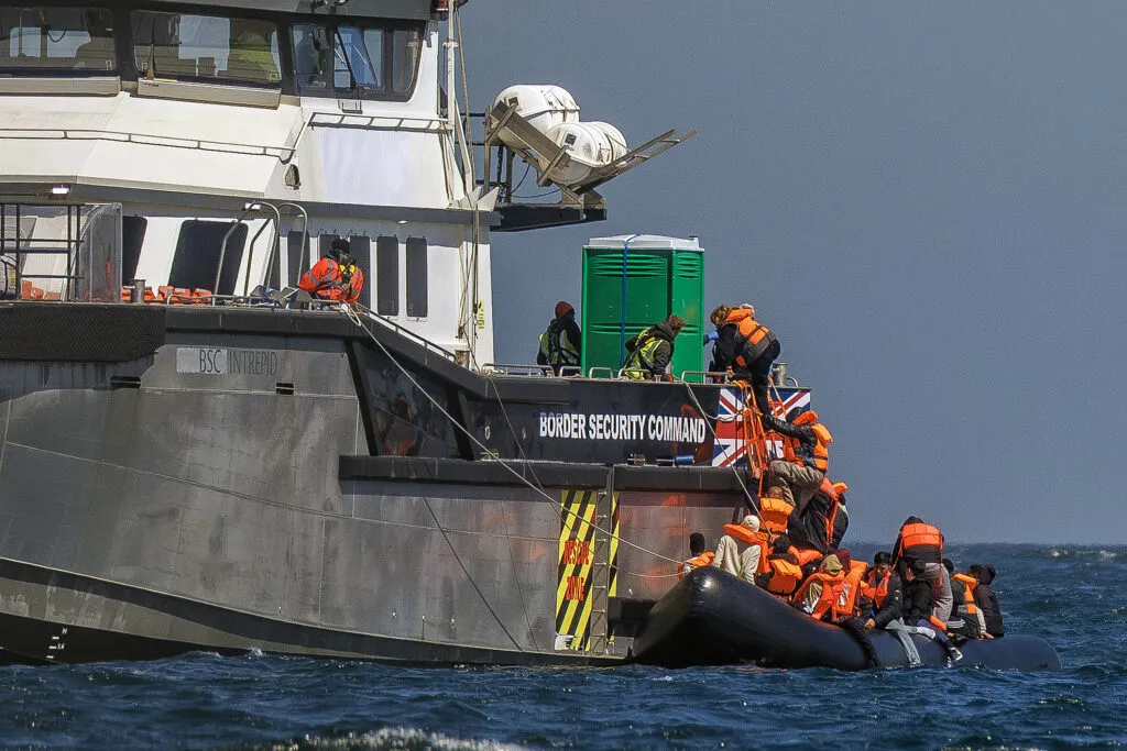 Des migrants sur un canot gonflable montent à bord d’un navire des garde‑côtes britanniques après avoir traversé la Manche depuis le nord de la France, le 27 avril 2026.